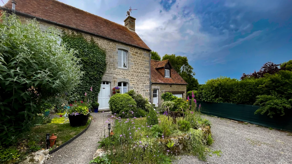 Entrée principale gîte normandie avec jardin d'accueil fleuri et chemin paysager - location basse normandie