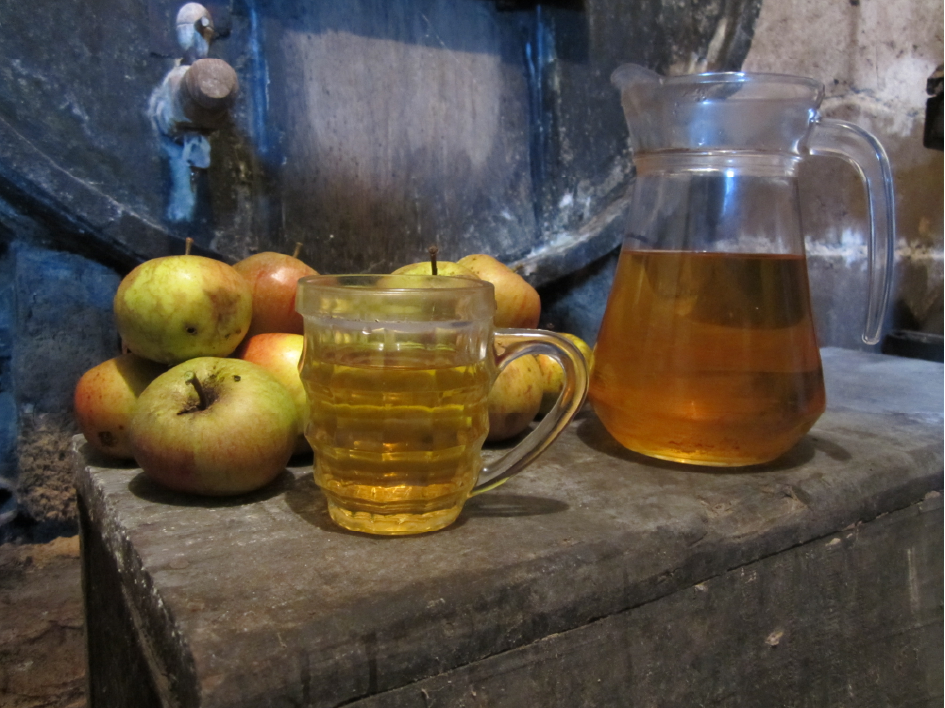 Verre de cidre normand artisanal avec pichet et pommes fraîches