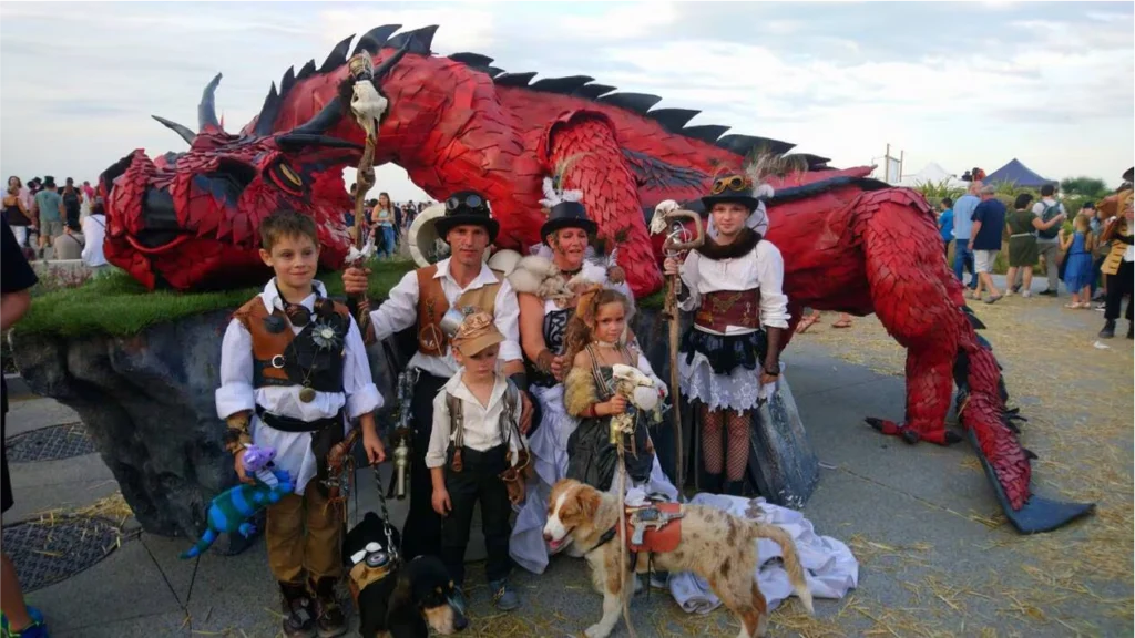 Famille en costumes médiévaux et fantastiques devant un dragon géant au festival Cidre et Dragon
